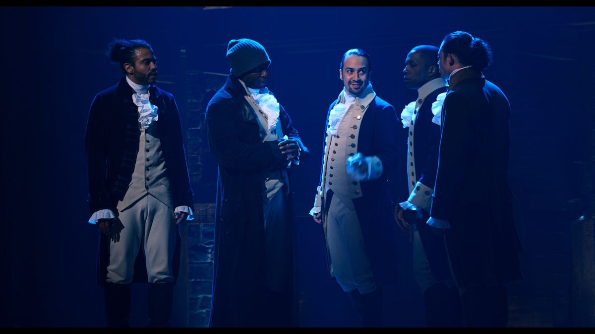 Un gruppo di membri del cast si trova intorno a Lin-Manuel Miranda a Hamilton.