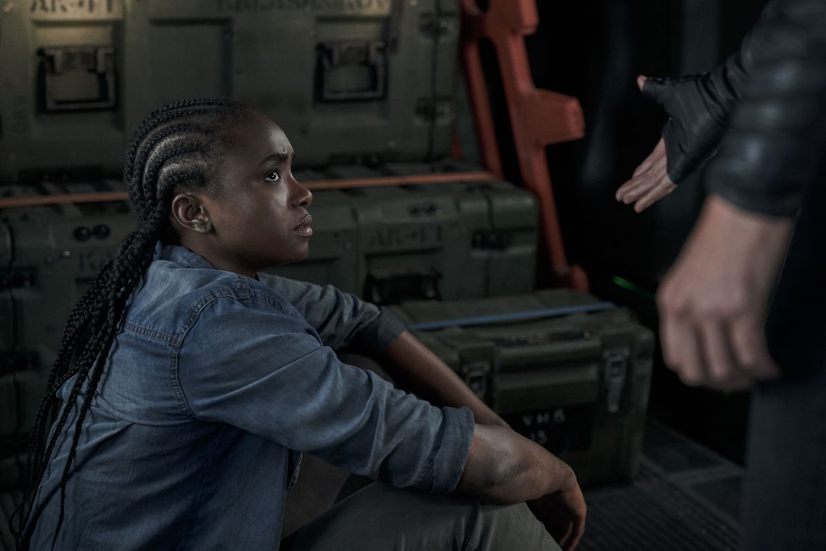 Kiki Layne siede tra armi e custodie di munizioni, lanciando un'occhiataccia a Charlize Theron in The Old Guard.