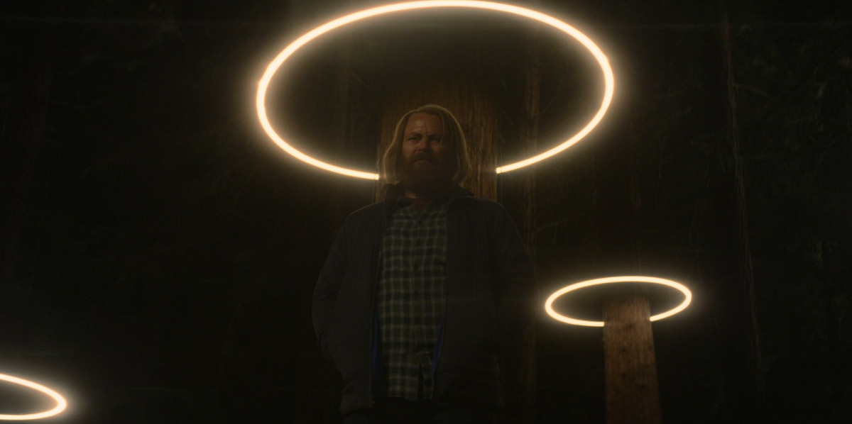 Un personaggio di Devs si trova sotto una luce, simile a un alone attorno alla sua testa