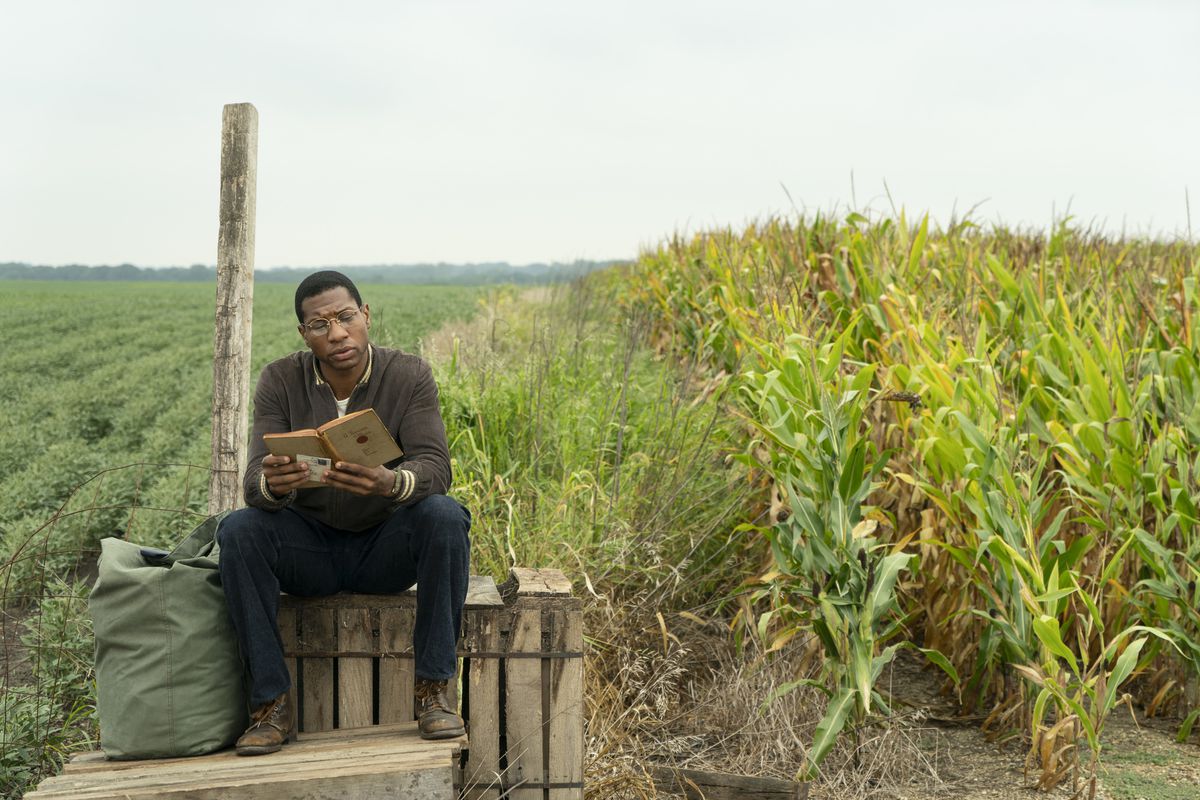 Jonathan Majors è seduto a leggere in un campo di grano nel paese di Lovecraft.