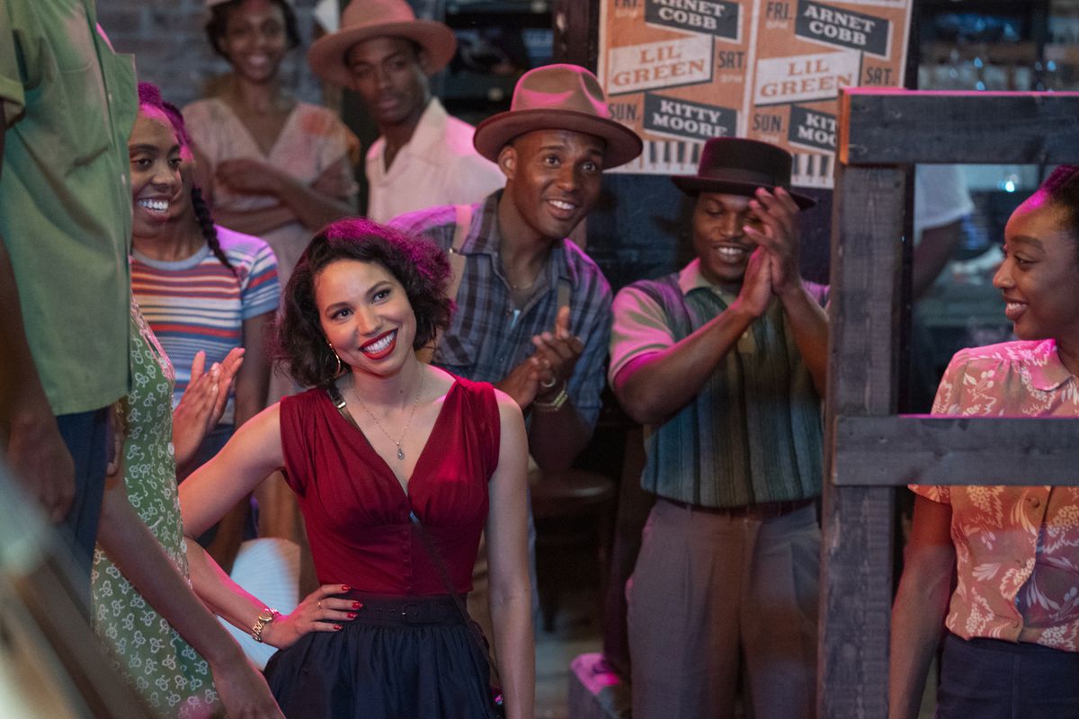 Jurnee Smollett sta sorridendo in mezzo a una folla di persone che applaudono a Lovecraft Country.