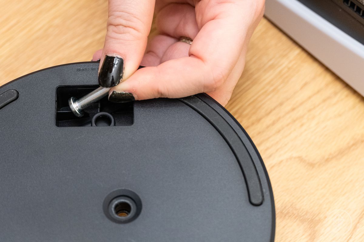 una mano prende la vite del supporto PlayStation 5 dal vano per esso all'interno del supporto