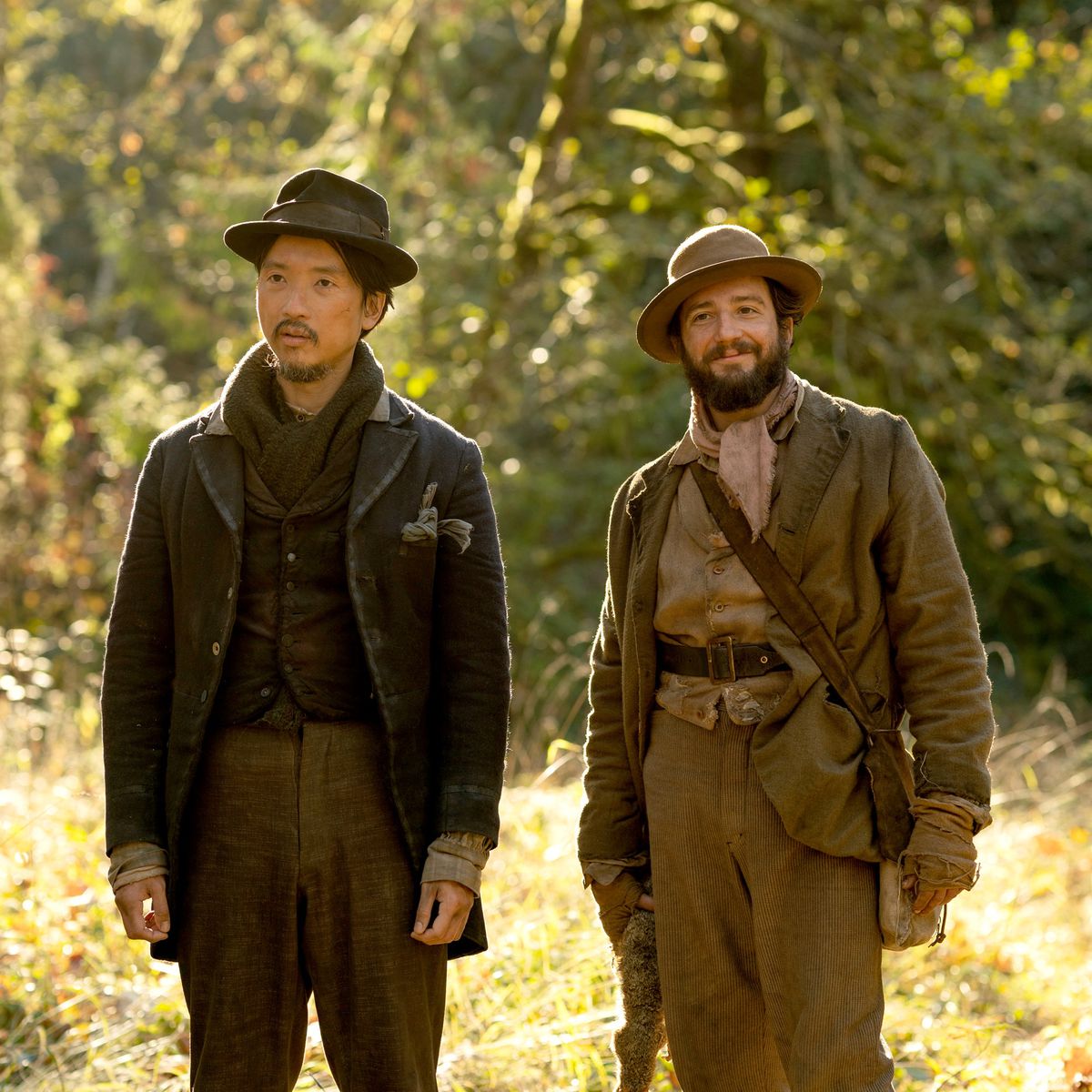 John Magaro e Orion Lee indossano cappotti marroni sciatti in First Cow