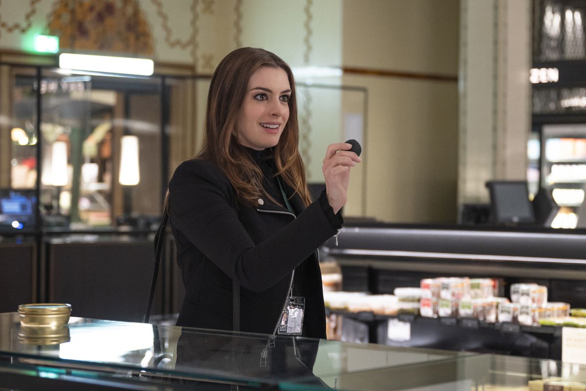 Anne Hathaway mostra un piccolo oggetto ad Harrods in Locked Down