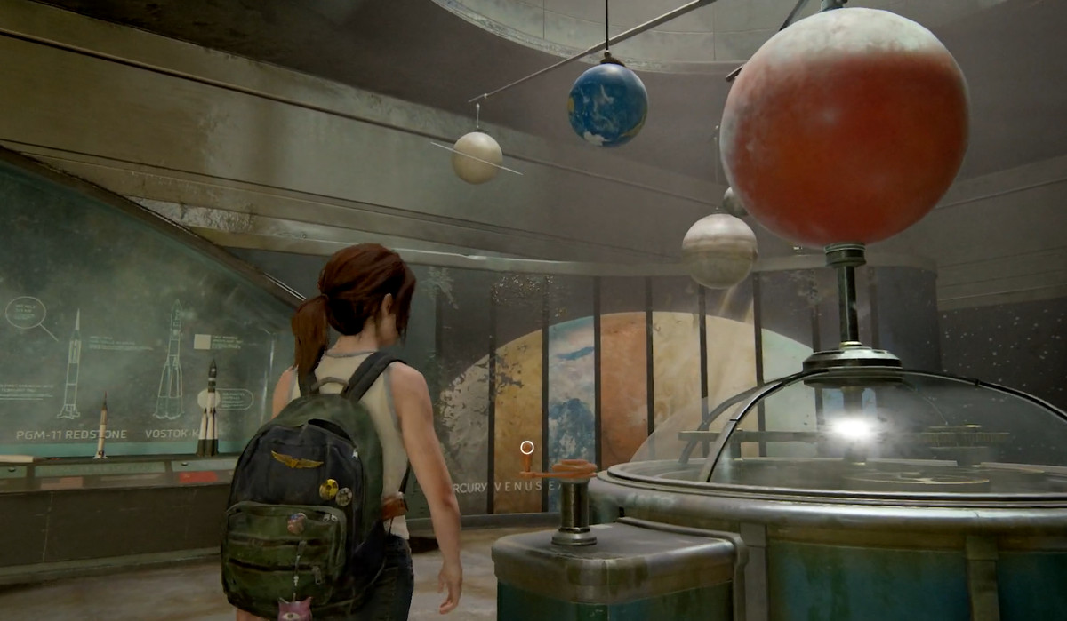 Ellie di The Last Of Us Parte 2 in una canotta in un museo che guarda i pianeti