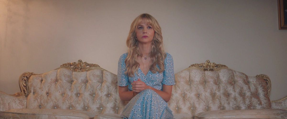 Cassie (Carey Mulligan) si siede su un divano nel soggiorno dei suoi genitori in Promising Young Woman