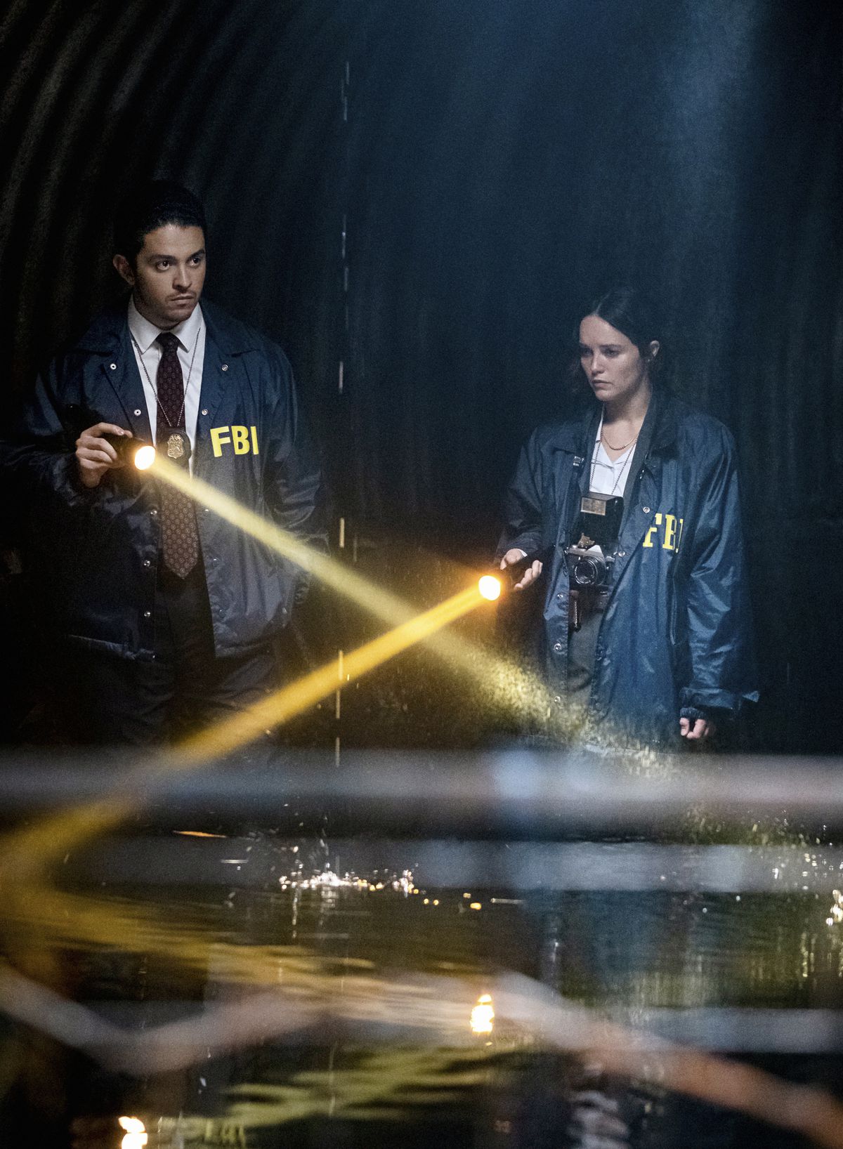 Clarice Starling e il collega agente dell'FBI Tomas Esquivel puntano le torce sull'acqua in uno spazio buio a Clarice.