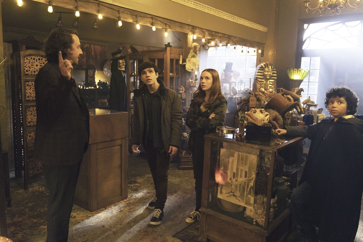 Tre bambini di Curse of the Shadows vengono istruiti dal proprietario del negozio di magia di Sardo.