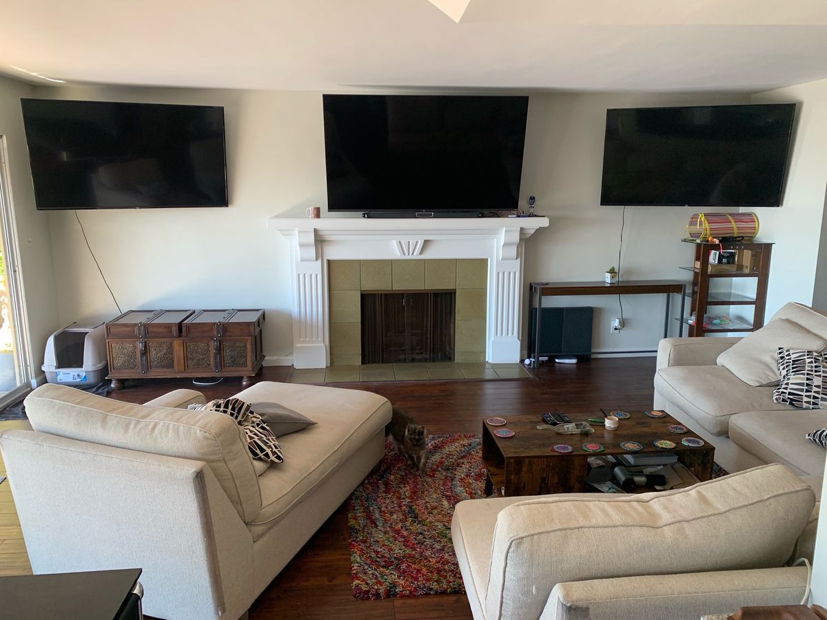 una foto di un soggiorno con tre televisori montati su una parete sopra un caminetto