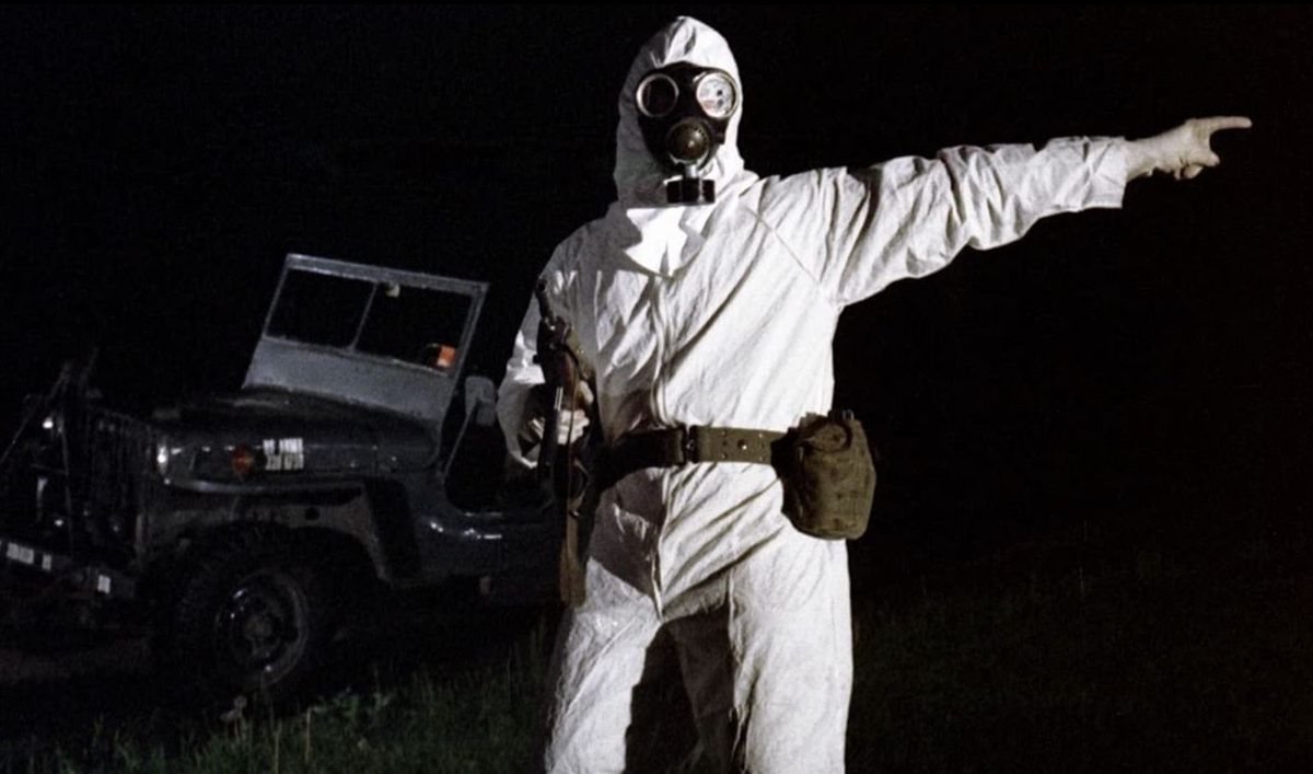 The Crazies: un uomo con una tuta ignifuga indica fuori campo mentre impugna una pistola