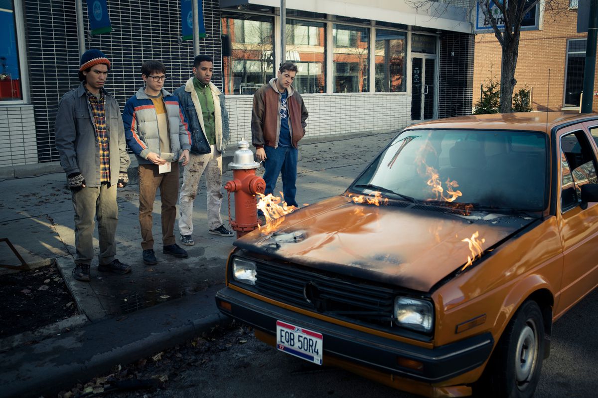 Cherry e il suo equipaggio sono accanto a un'auto arancione mentre il cofano prende fuoco