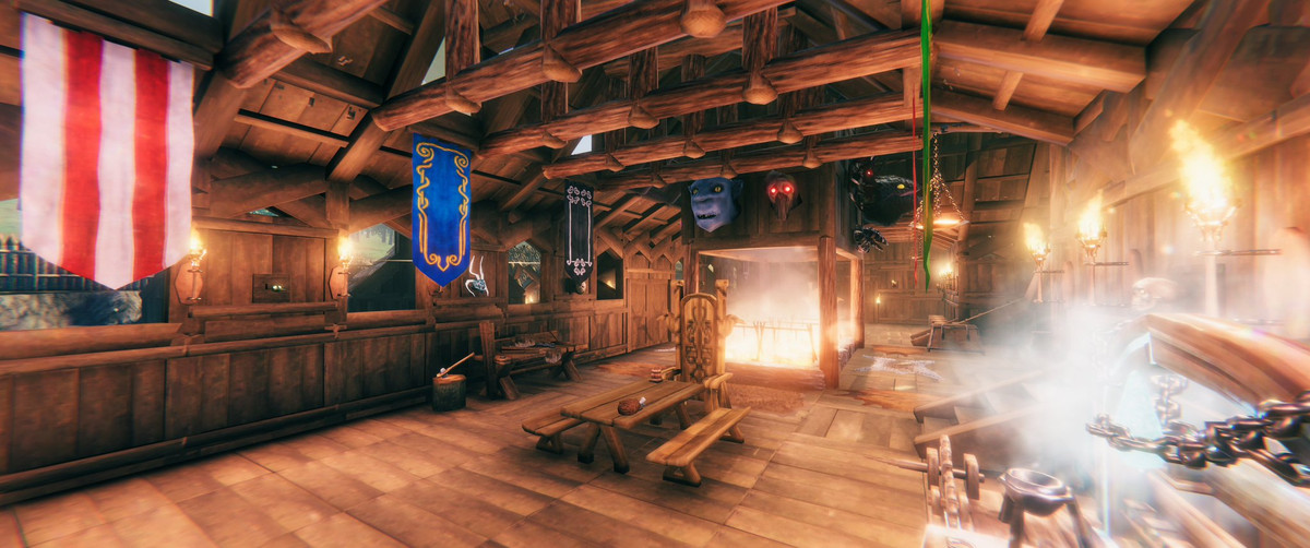 Valheim - un'inquadratura interna di una sala principale, decorata con trofei e striscioni colorati.