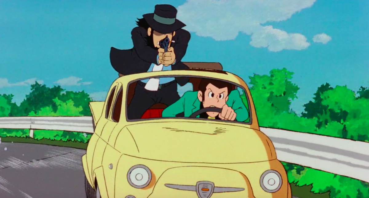 Lupin e il suo partner Jigen sfrecciano lungo l'autostrada a bordo di un'auto gialla in Il castello di Cagliostro di Hayao Miyazaki.