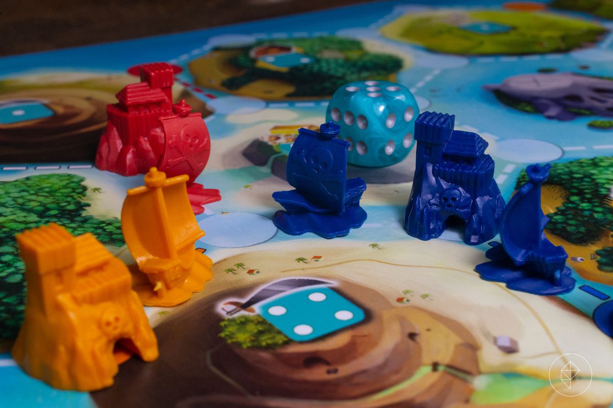 Pirate ships and secret hideouts in blue, orange, and red. A sea-colored die sits in the background.