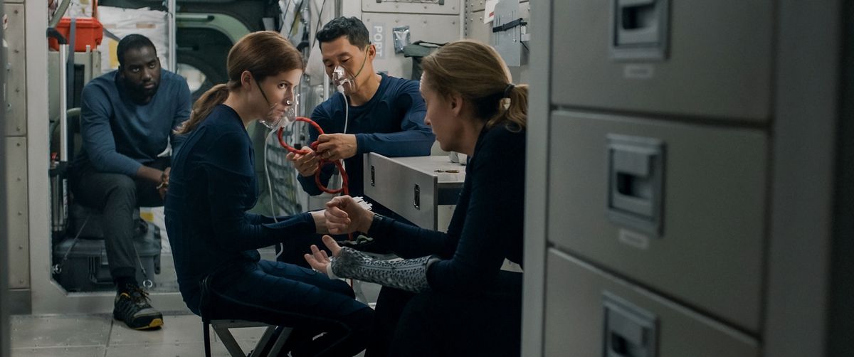 Il cast di Stowaway nella loro cambusa, con Anna Kendrick e Daniel Dae Kim che indossano maschere di ossigeno, Toni Collette seduto vicino a loro e Shamier Anderson seduto sullo sfondo