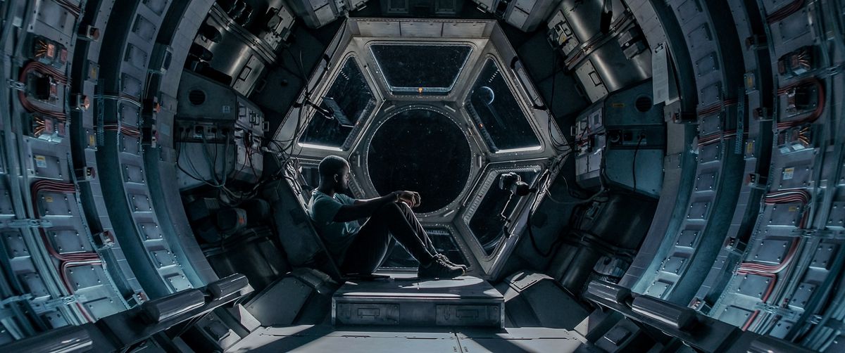 Shamier Anderson siede da solo davanti a una finestra sullo spazio a Stowaway