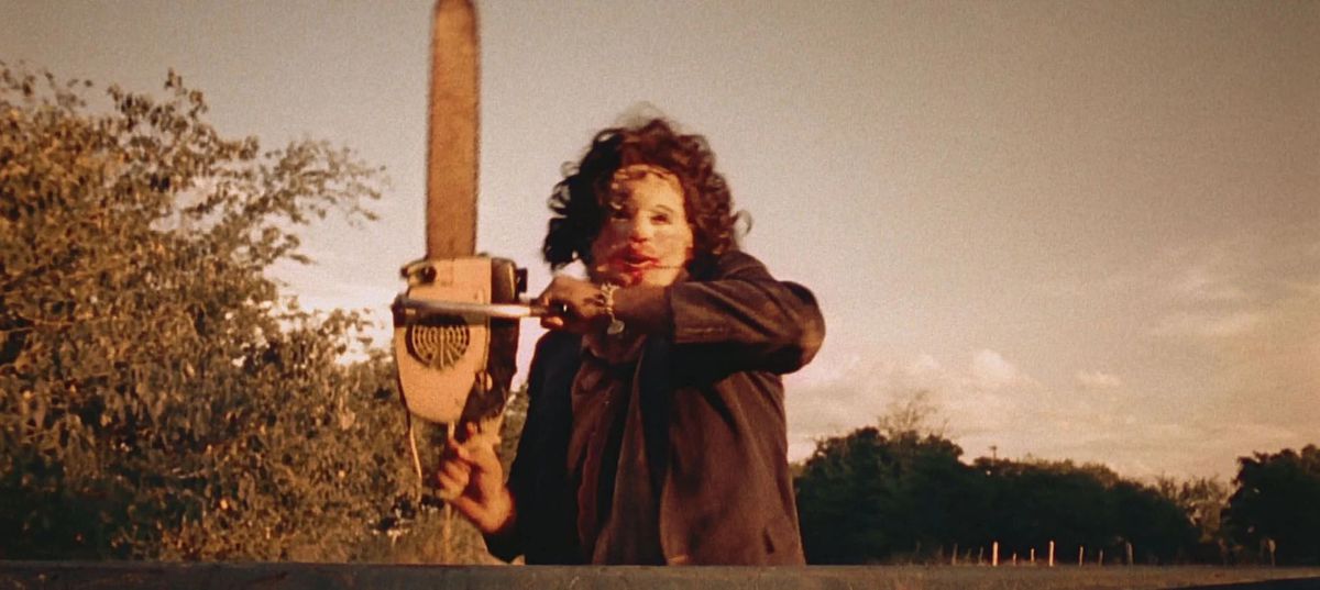 Leatherface insegue un camion mentre brandisce una motosega.
