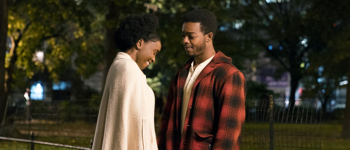 The leads of If Beale Street Could Talk face each other, smiling, in a park at night