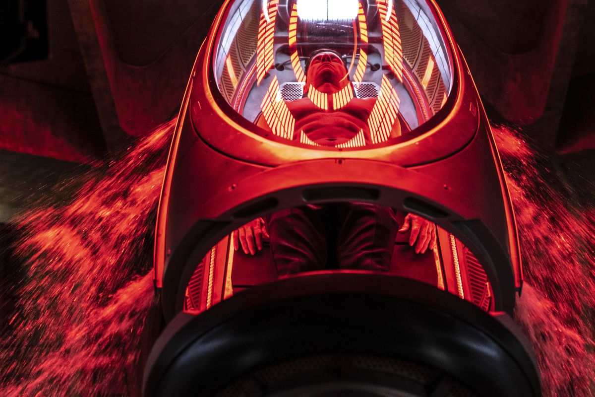 Mark Wahlberg giace a torso nudo all'interno di una capsula di vetro e metallo inondata di luce rossa e gialla in Infinite