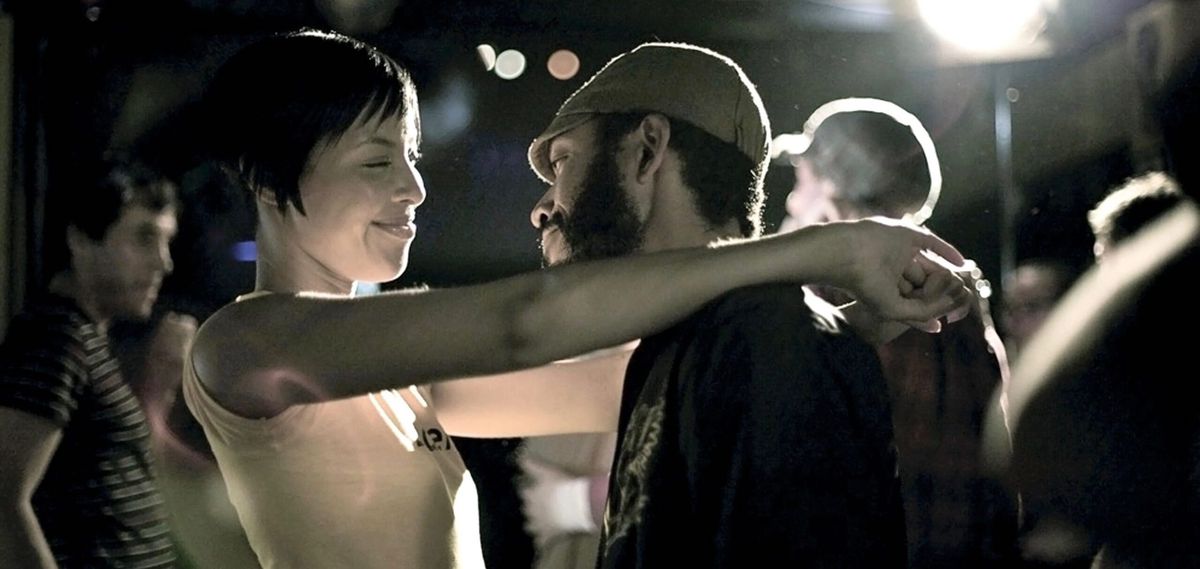 The Black leads of Medicine for Melancholy dance together in a crowd, smiling at each other