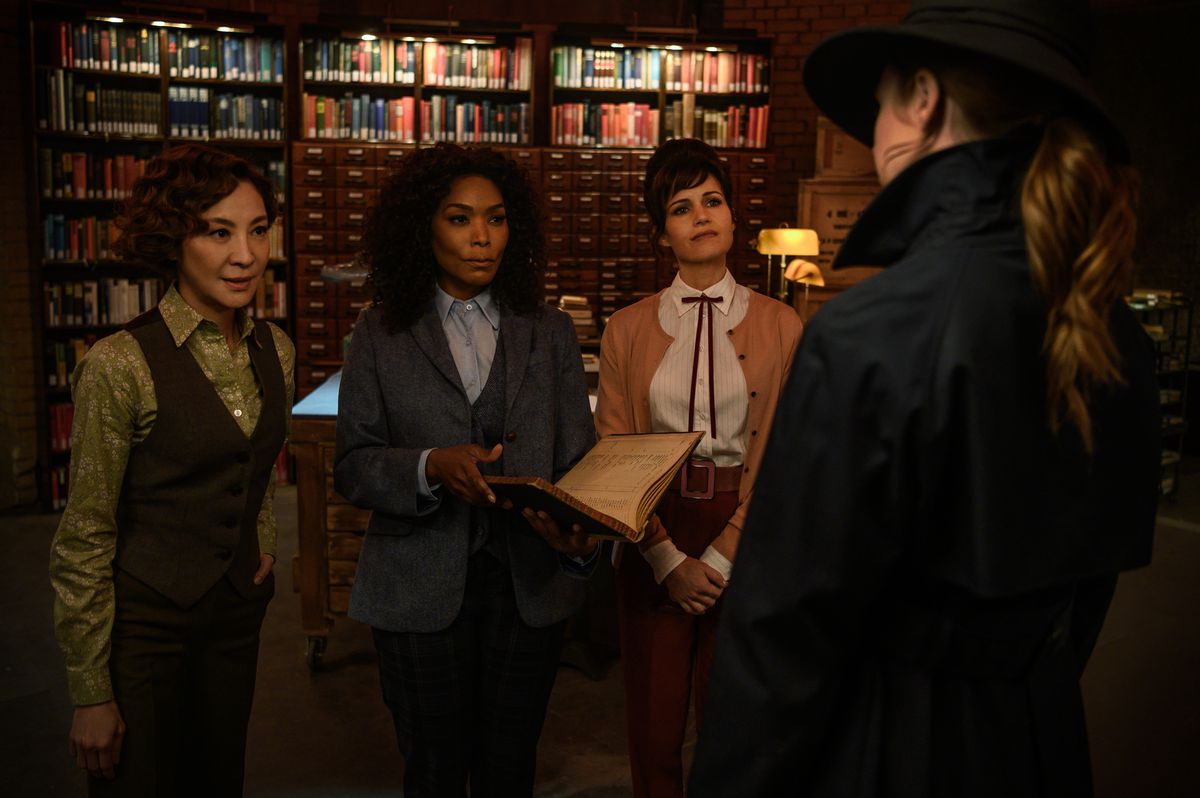 Karen Gillan, vista da dietro e con indosso un cappello e un trench, affronta un gruppo di armieri —Michelle Yeoh, Angela Bassett e Carla Gugino — in Gunpowder Milkshake