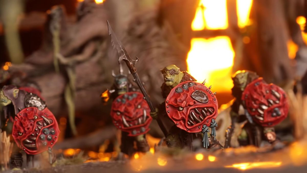 Un gruppo di Orruks illuminato dalla luce del fuoco.