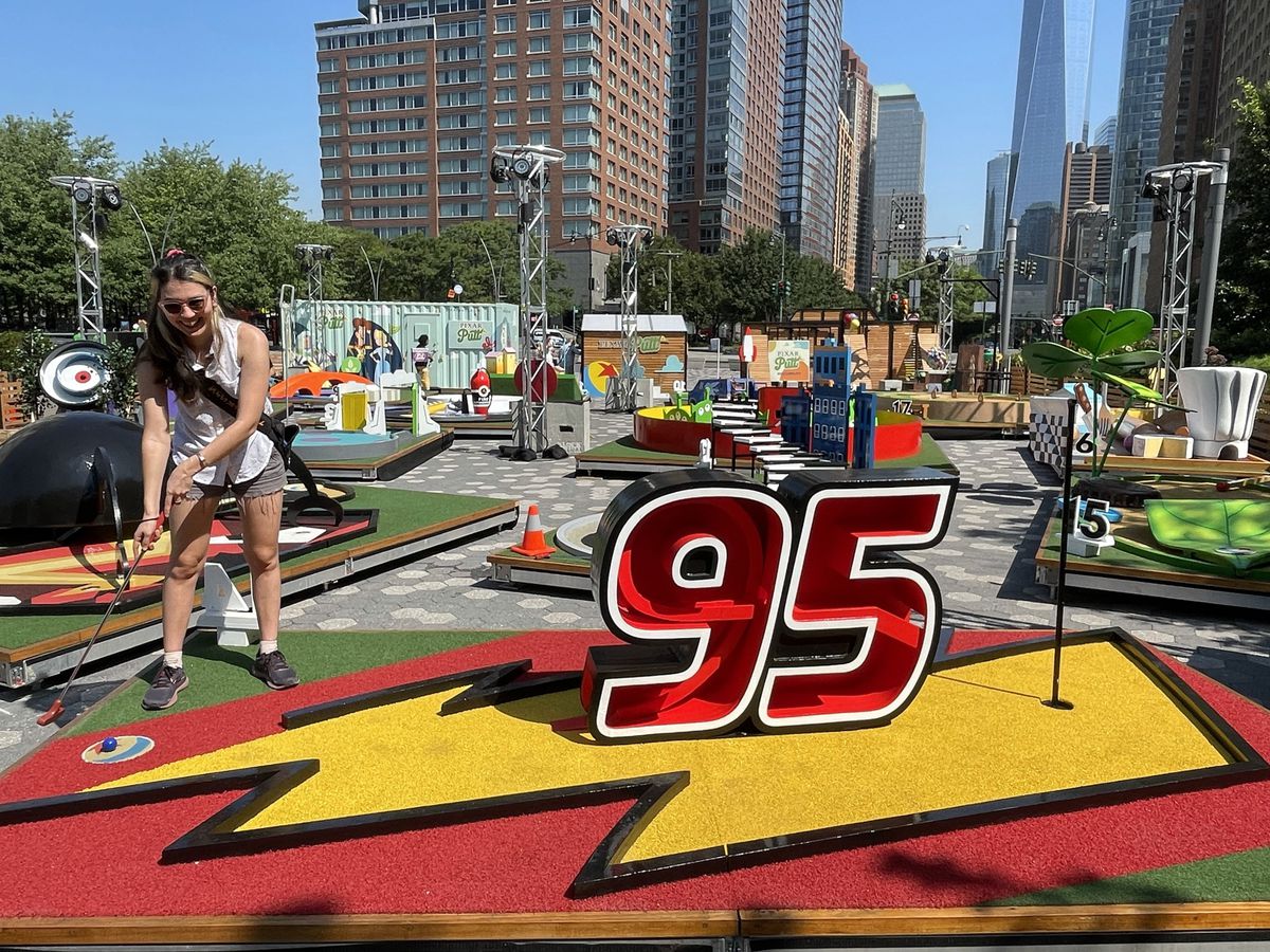 petrana in piedi di fronte a un campo da minigolf a tema Saetta Mcqueen, con un grande sorriso
