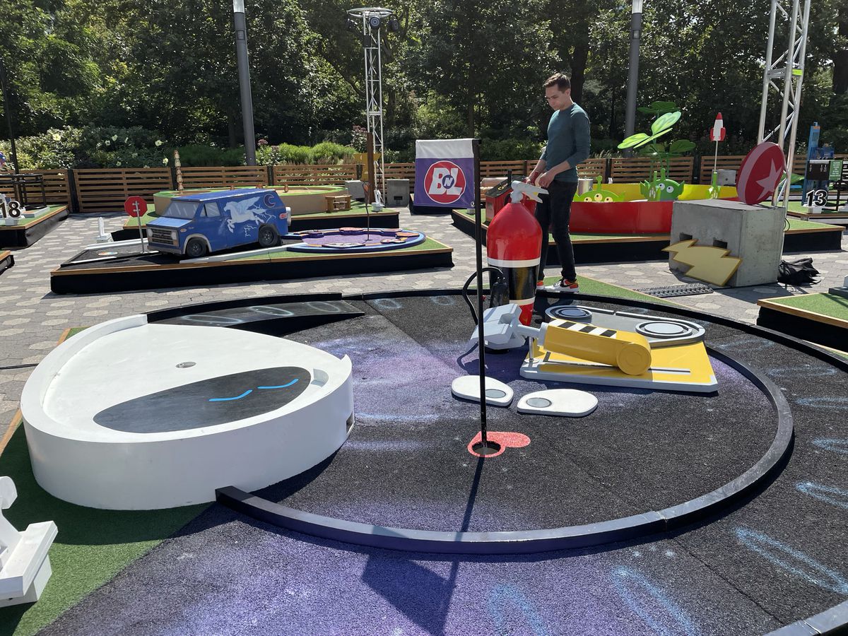 un campo da minigolf circolare progettato per assomigliare al WALL-E della Pixar;  Austen gli sta accanto
