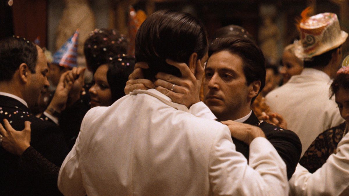 Michael Corleone abbraccia un altro uomo in modo minaccioso a una festa di Capodanno in Il Padrino Parte II. 