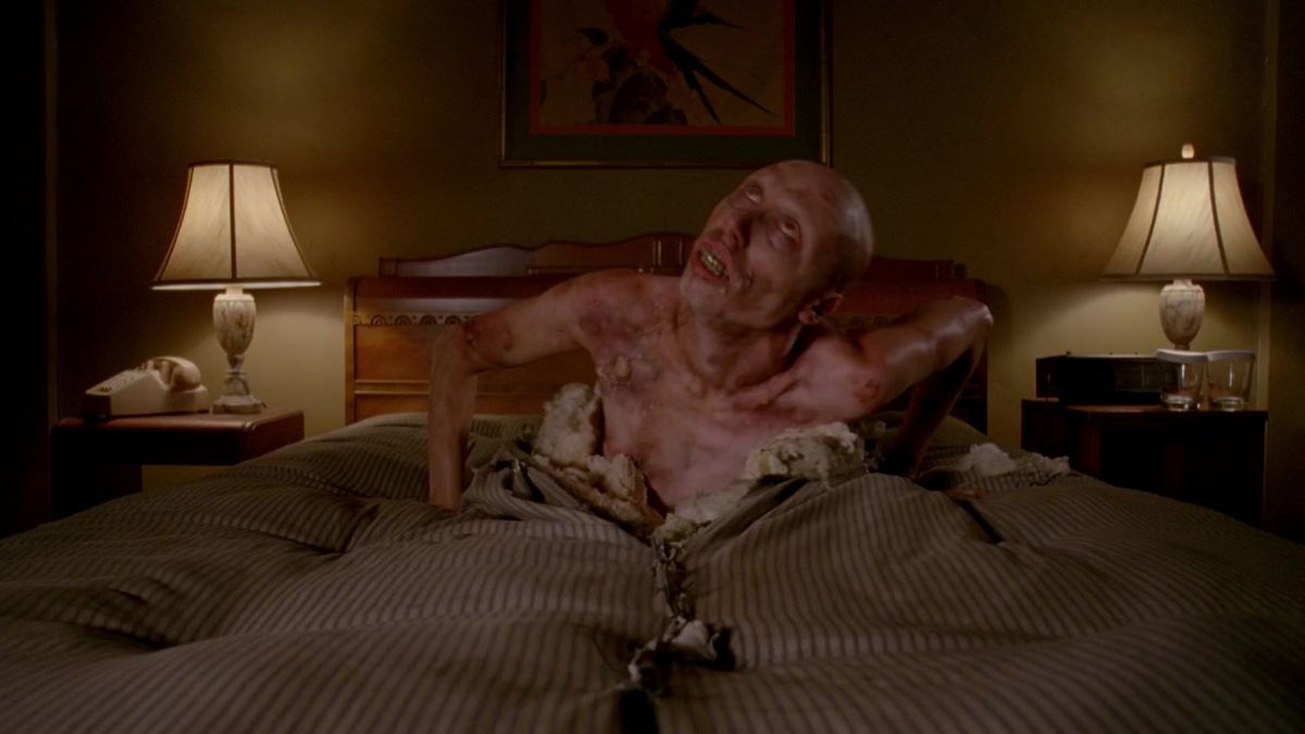 a man with red, blistering skin crawling his way out of a mattress