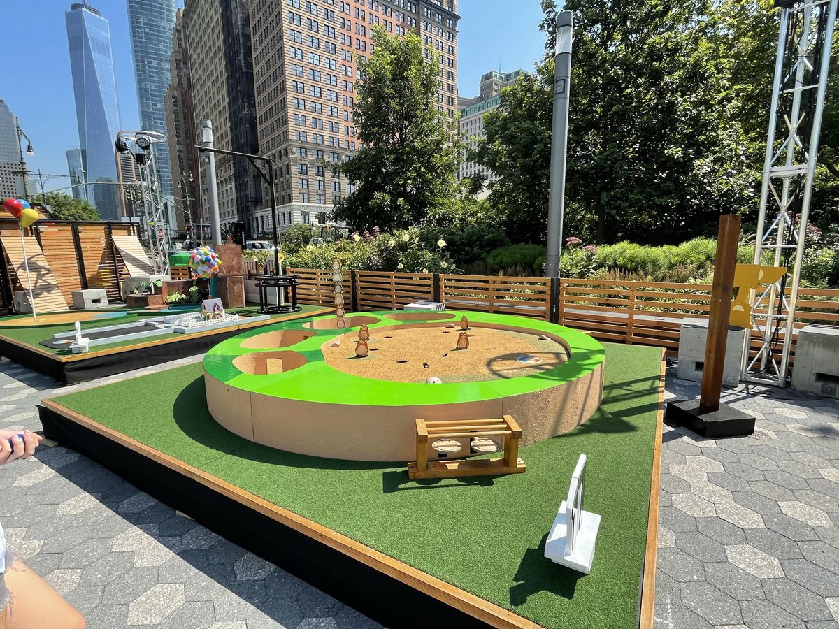 una buca da golf circolare verde con dentro piccoli gopher