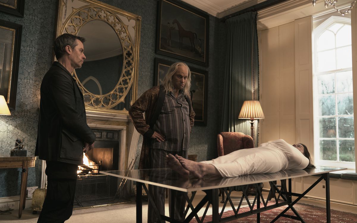 Due uomini stanno sopra il corpo avvolto di una donna su un tavolo nella Zona 414