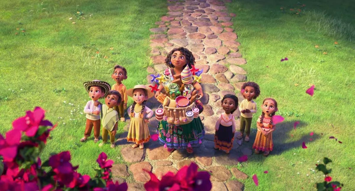 Mirabel Madrigal (Stephanie Beatriz) holding a colorful gift basket while surrounded by a group of children.