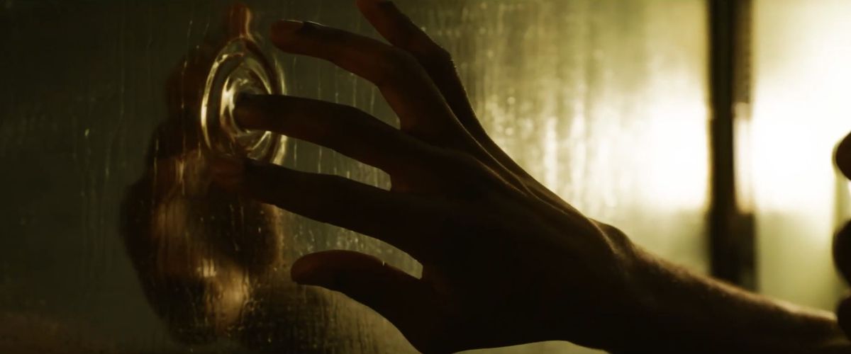 yahya abdul-mateen ii’s hand touches a liquid mirror in The Matrix Resurrections