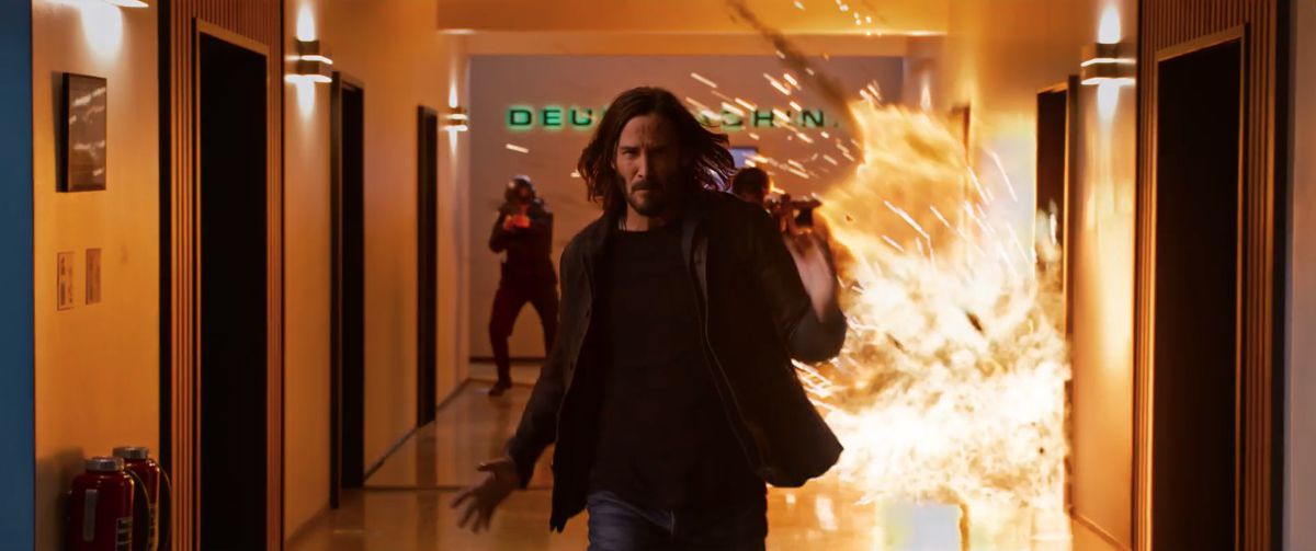 Keanu Reeves’ Neo runs away from a blast in The Matrix Resurrections