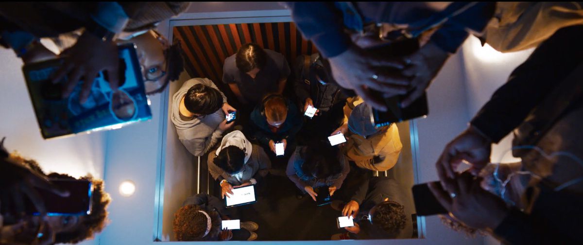 The Matrix Resurrections people on their phones in an elevator with Neo