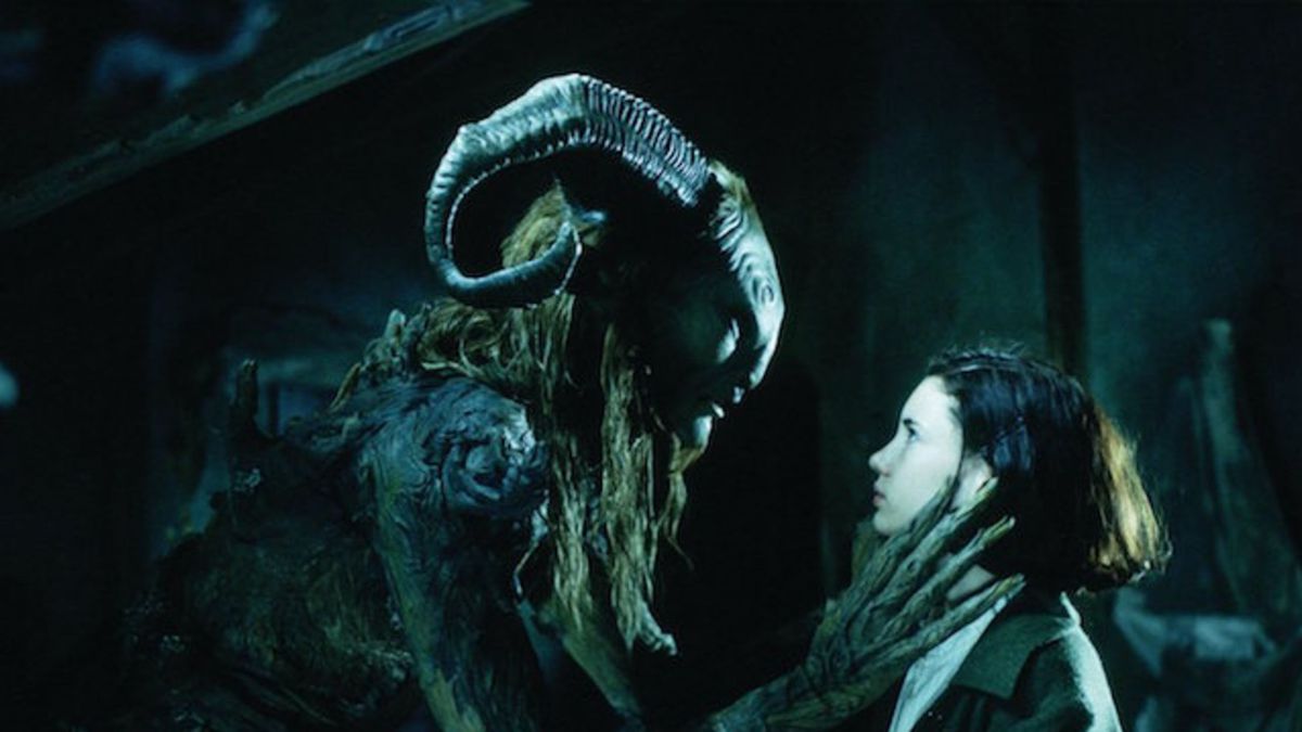A monster with large horns and long fingers crouches down in front of a young girl.