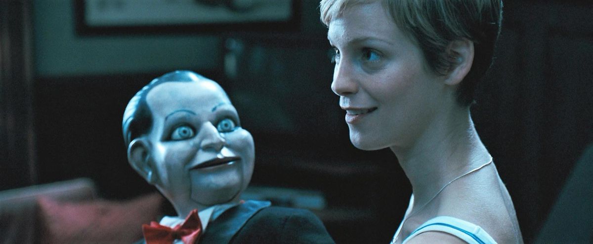 Un fantoccio ventriloquo guarda minaccioso una donna ignara