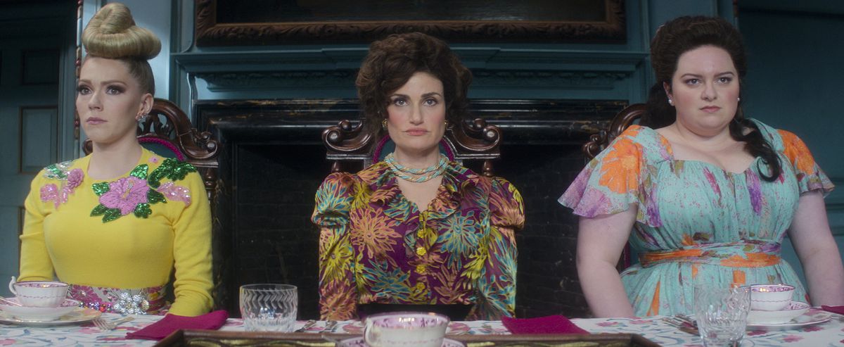 La matrigna di Cenerentola (Idina Menzel) e le sorellastre siedono in fila e sembrano scontrose in Cenerentola di Amazon