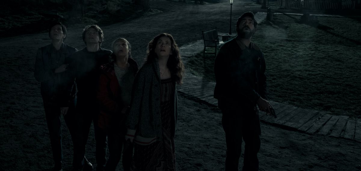 Un gruppo di persone che camminano su un oscuro sentiero notturno guardano a bocca aperta insieme durante la messa di mezzanotte