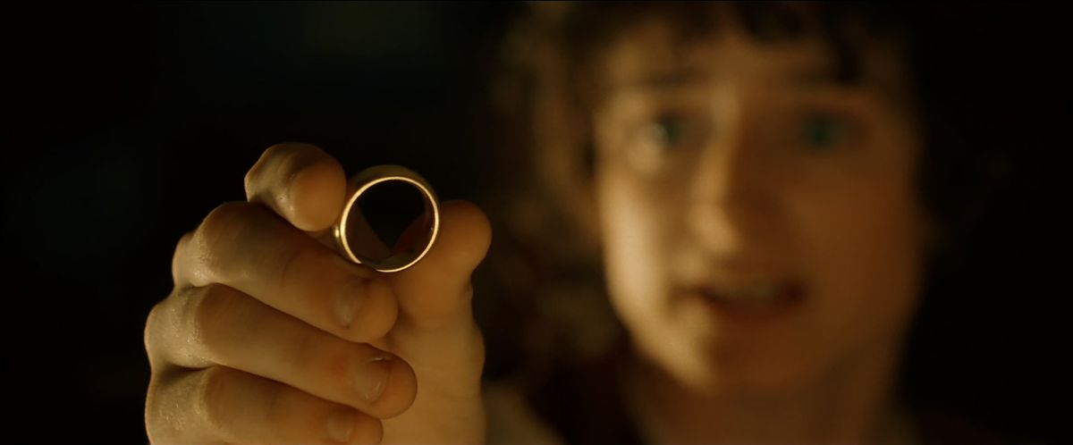 Frodo (out of focus) holds out the One Ring (in focus) with a pleading gesture in The Fellowship of the Ring.