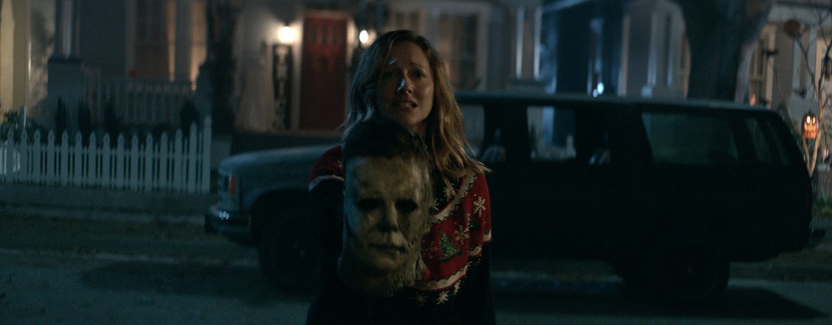 Una donna dall'aspetto teso regge la maschera di Michael Myers in Halloween Kills