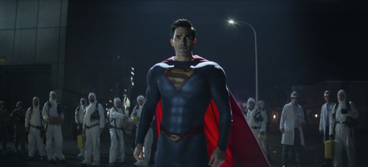 Tyler Hoechlin in his Superman costume stands in front of a group of hazmat-suited workers at night in Superman & Lois