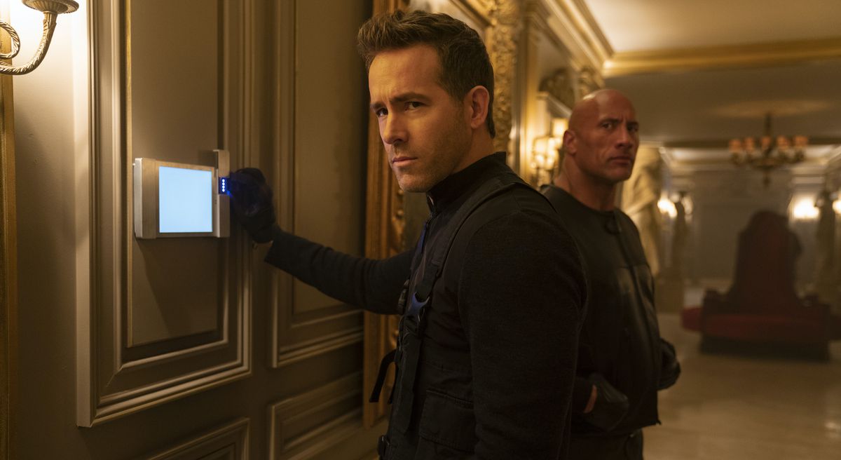 Ryan Reynolds gioca con un allarme elettronico e Dwayne Johnson si nasconde sullo sfondo in Red Notice