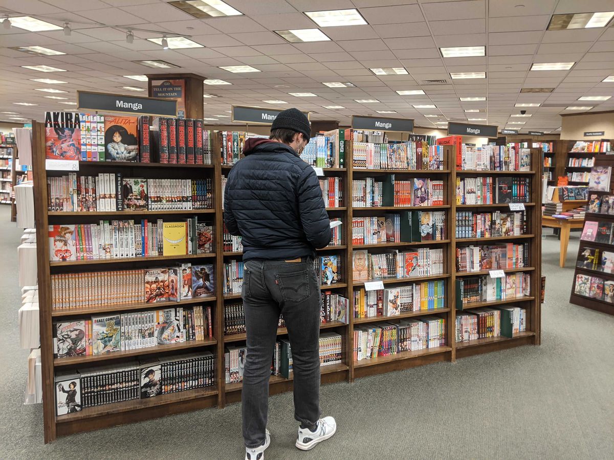 Un giovane in piedi che sfoglia alcuni manga nella sezione manga di Barnes and Noble