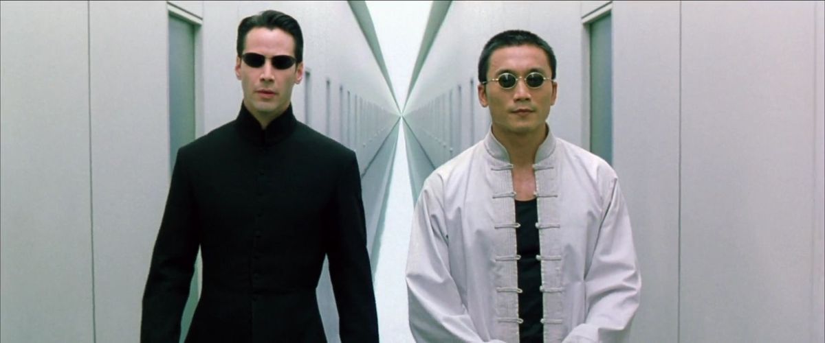 Seraph e Neo camminano lungo un corridoio bianco in Matrix Reloaded