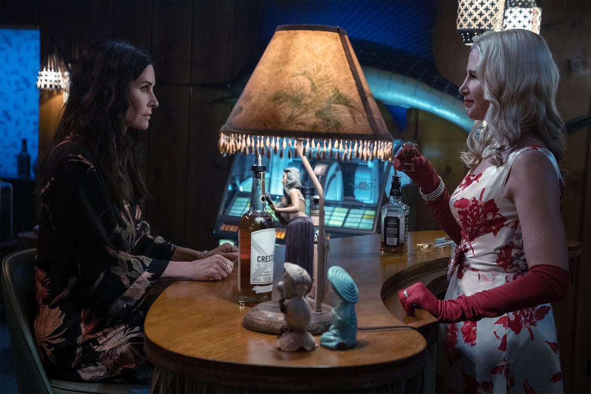 Rosemary (Mira Sorvino), Pat (Courteney Cox) standing in a hotel lobby desk in Shining Vale