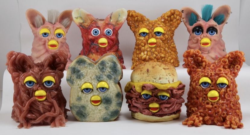 Un assortimento di Furbie modificati in modo grottesco, con la pelle che sembra fagioli o carne da pranzo, tra gli altri.