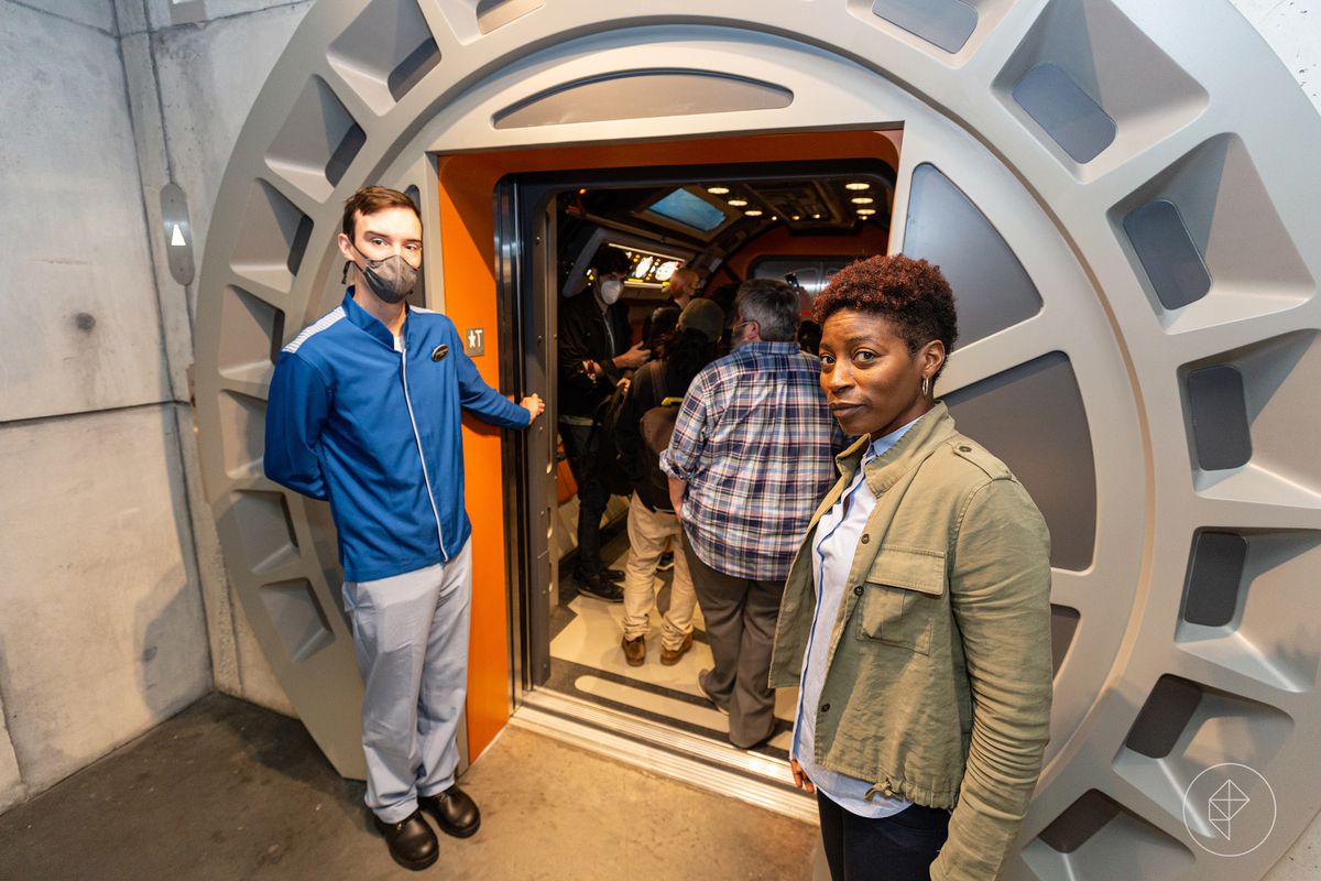 Il personale accoglie lo spettatore a bordo di una navetta. La porta si apre, svanendo nel muro.