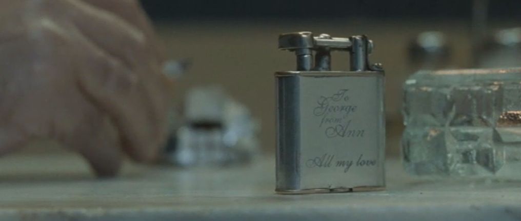 Un accendino inciso si trova su una scrivania.  L'incisione recita 